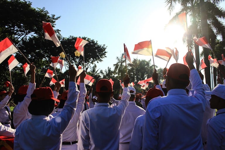 Crowd celebrating with Indonesian flags outdoors in Jakarta.